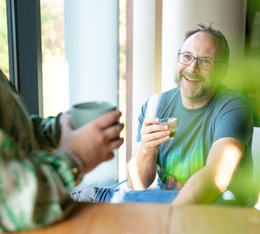 moment convivial autour dun cafe bio green lion coffee homme souriant degustant un espresso artisanal pres dune fenetre tasse floue en avantplan