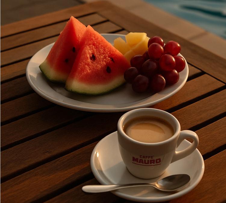 tasse de cafe espresso caffe mauro avec assiette de fruits sur table en bois